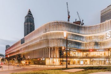 Talasasta metalna fasada modernog tržnog centra osvetljena u sumrak