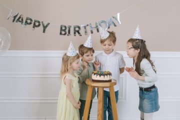 Deca sa rođendanskim kapicama ispod natpisa “Happy Birthday”